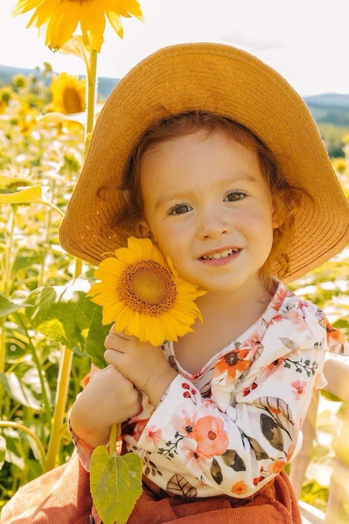 CHAMP beneficiary smiling in a sunflower field